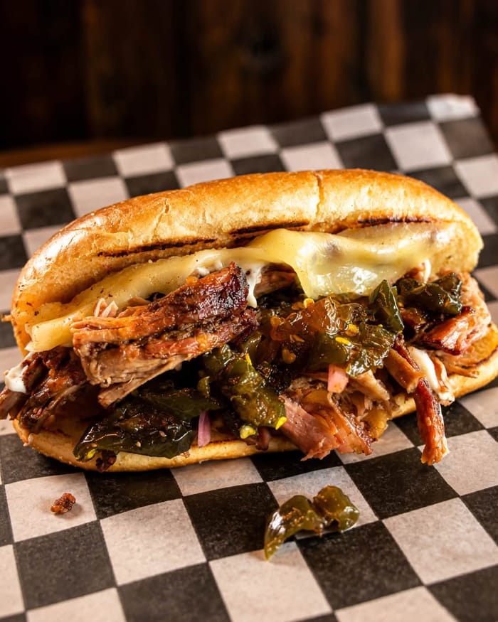 Brisket Philly sandwich with melted cheese and jalapeños on a toasted roll